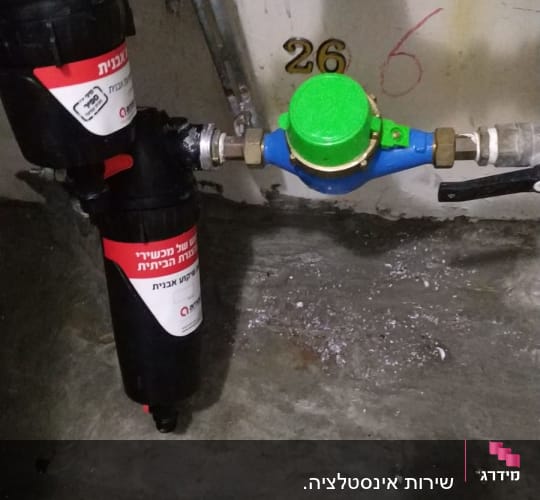 מד מים עם מכסה ירוק וצינורות מחוברים